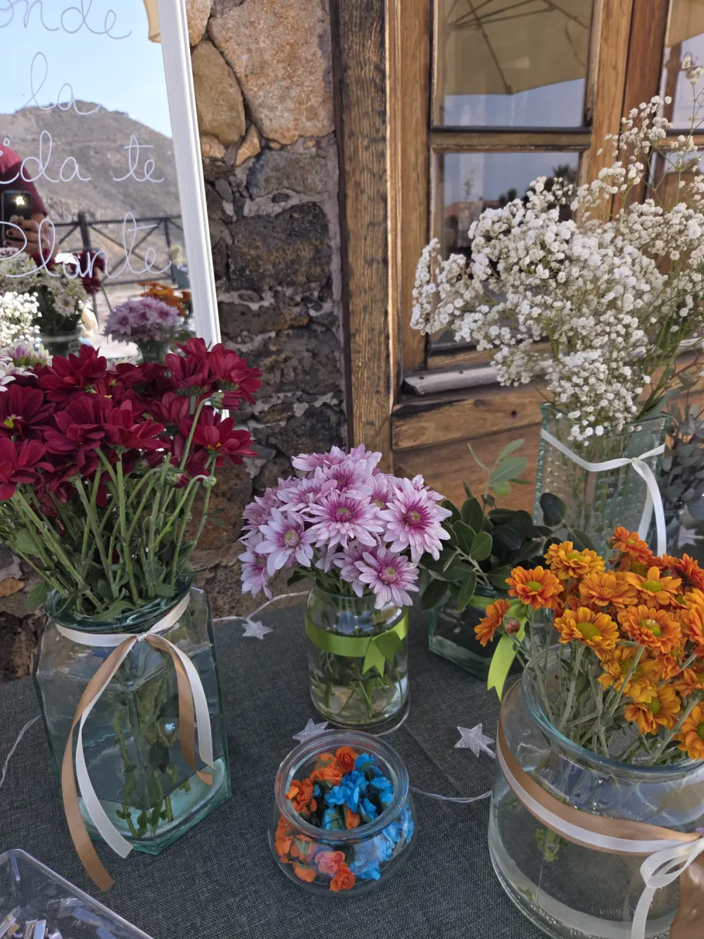 Botes de cristal con crisantemos rojos, rosas y naranjas